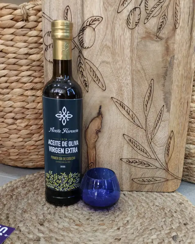 Botella de Aceite Herencia junto a una copa azul de cata de aceite